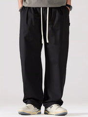Men's black oversized casual pants with a drawstring waist and pockets.