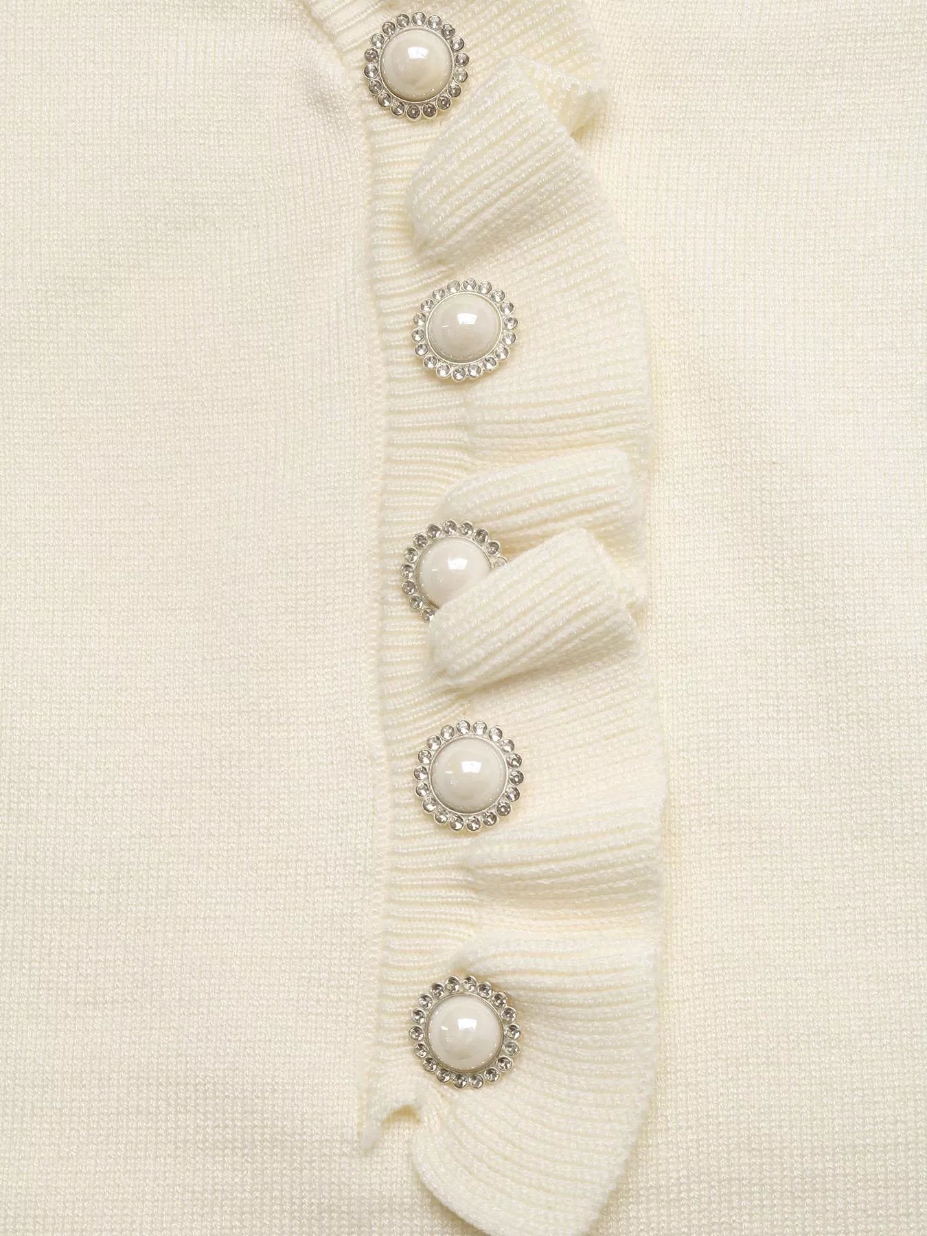 Close up of cream knit top ruffle placket with pearl and crystal buttons detail
