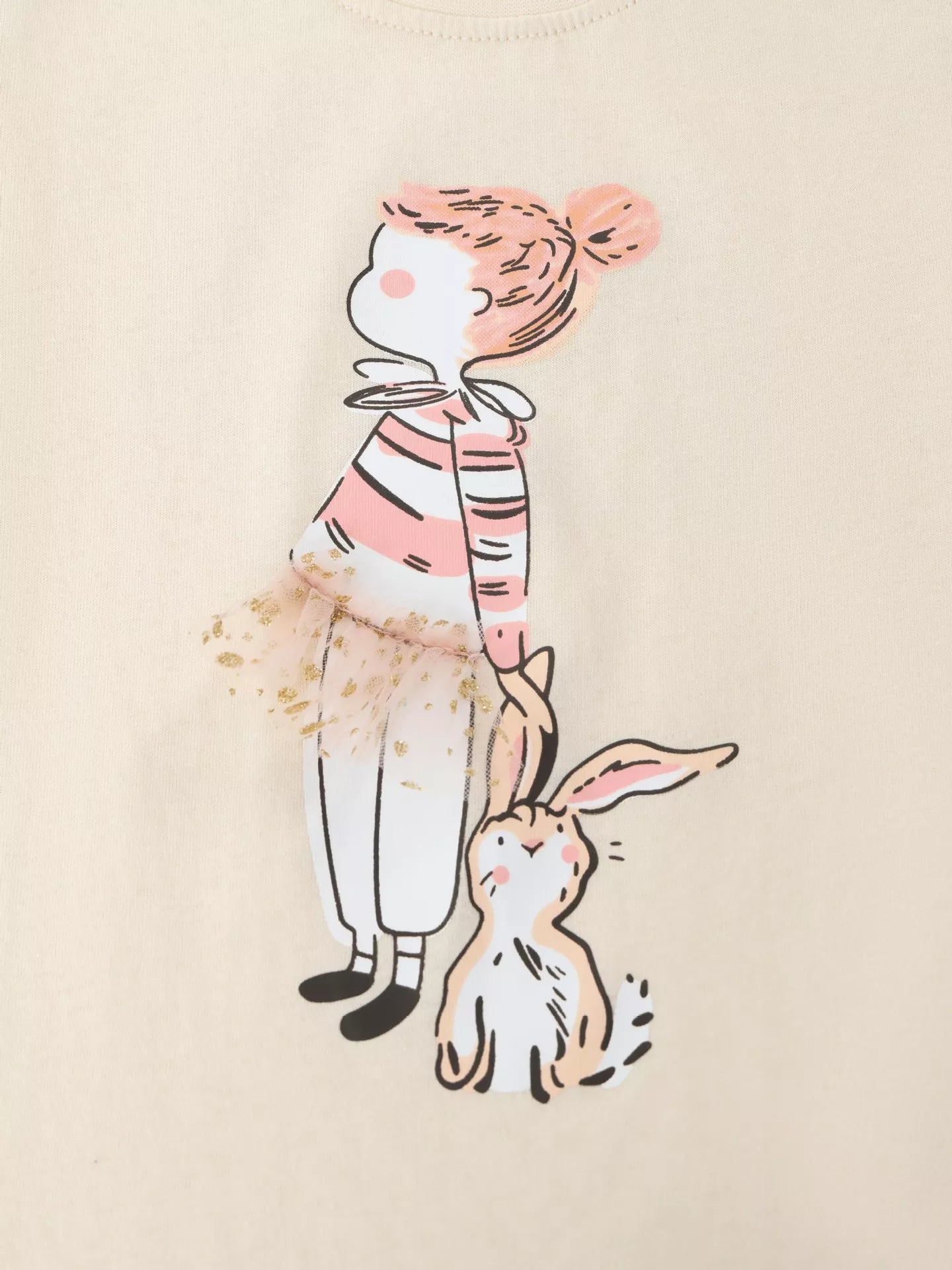 Close up of the cream T-shirt graphic showing a striped top, tulle skirt and a small rabbit
