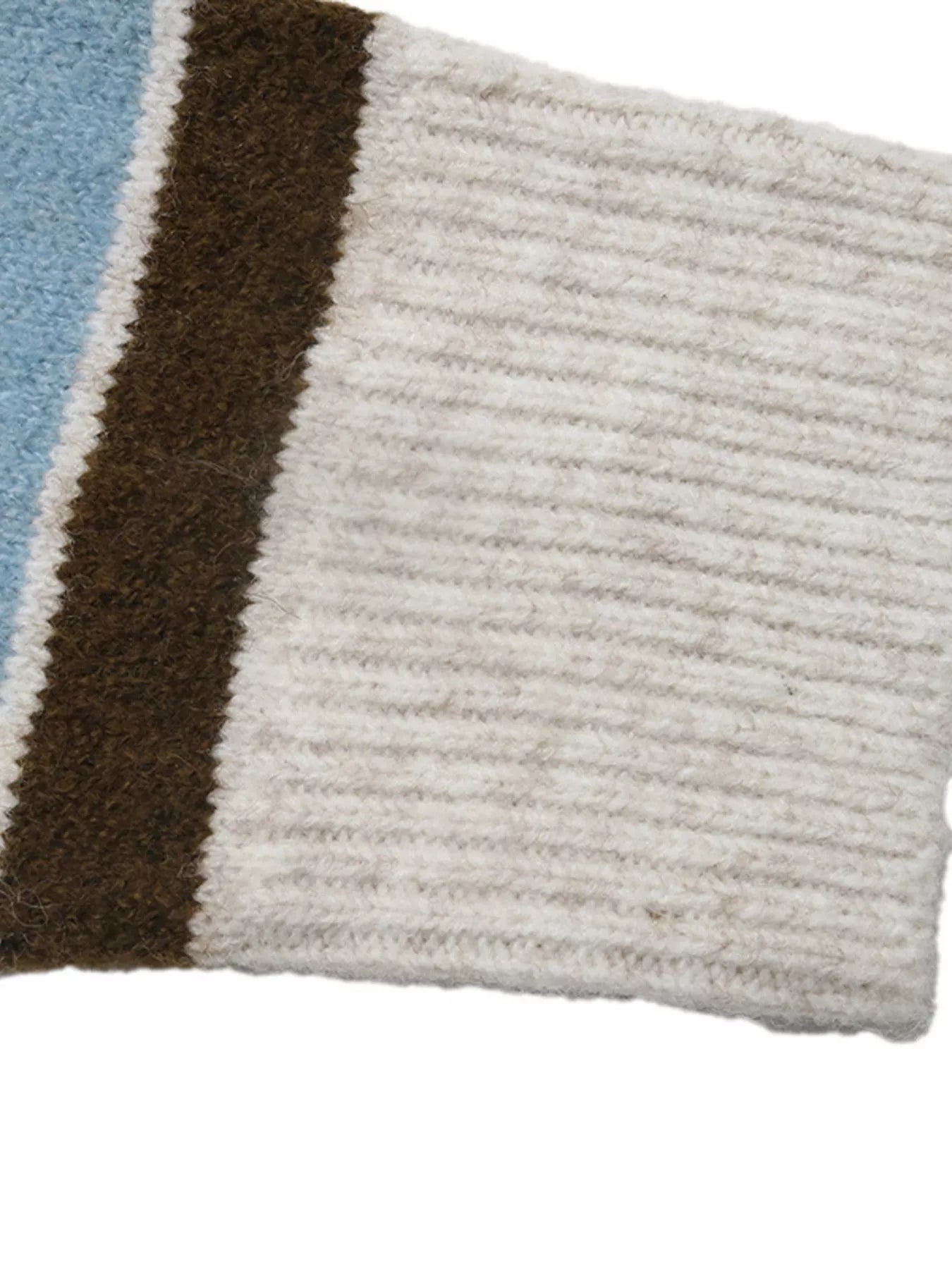 Close up of cream ribbed cuff on blue and brown striped knit sleeve.