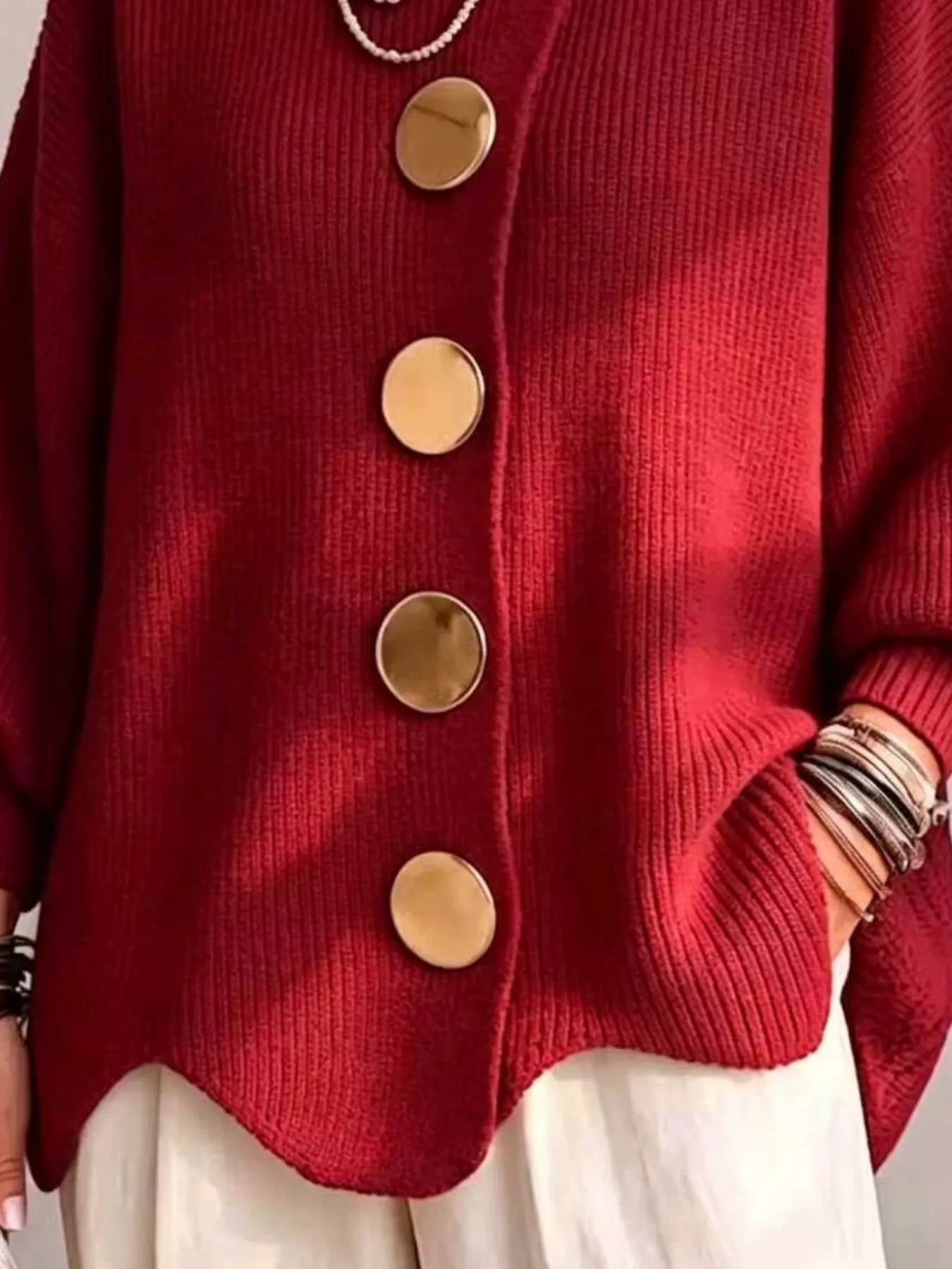 Close up of the deep red cardigan gold buttons and scalloped hem