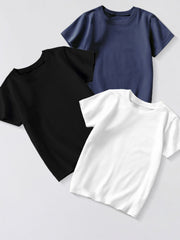 Three plain children's crew neck T-shirts in dark navy, black and white, arranged overlapping in a flat lay