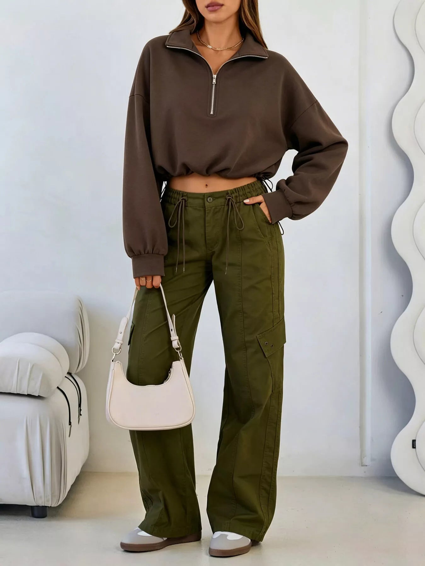 Full length front view of brown half zip sweatshirt with hand in pocket and olive cargo trousers