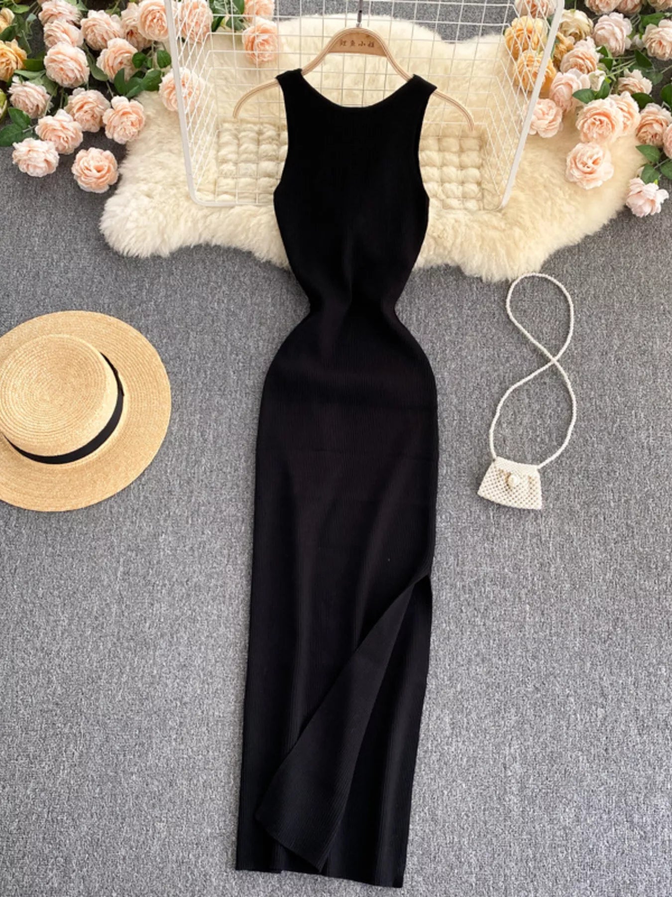 Black sleeveless knit bodycon midi dress, front view with side slit on hanger