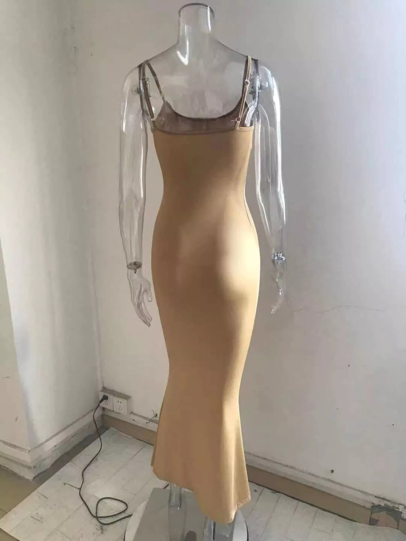 Back view of a camel spaghetti strap bodycon maxi dress on a clear mannequin showing thin shoulder straps