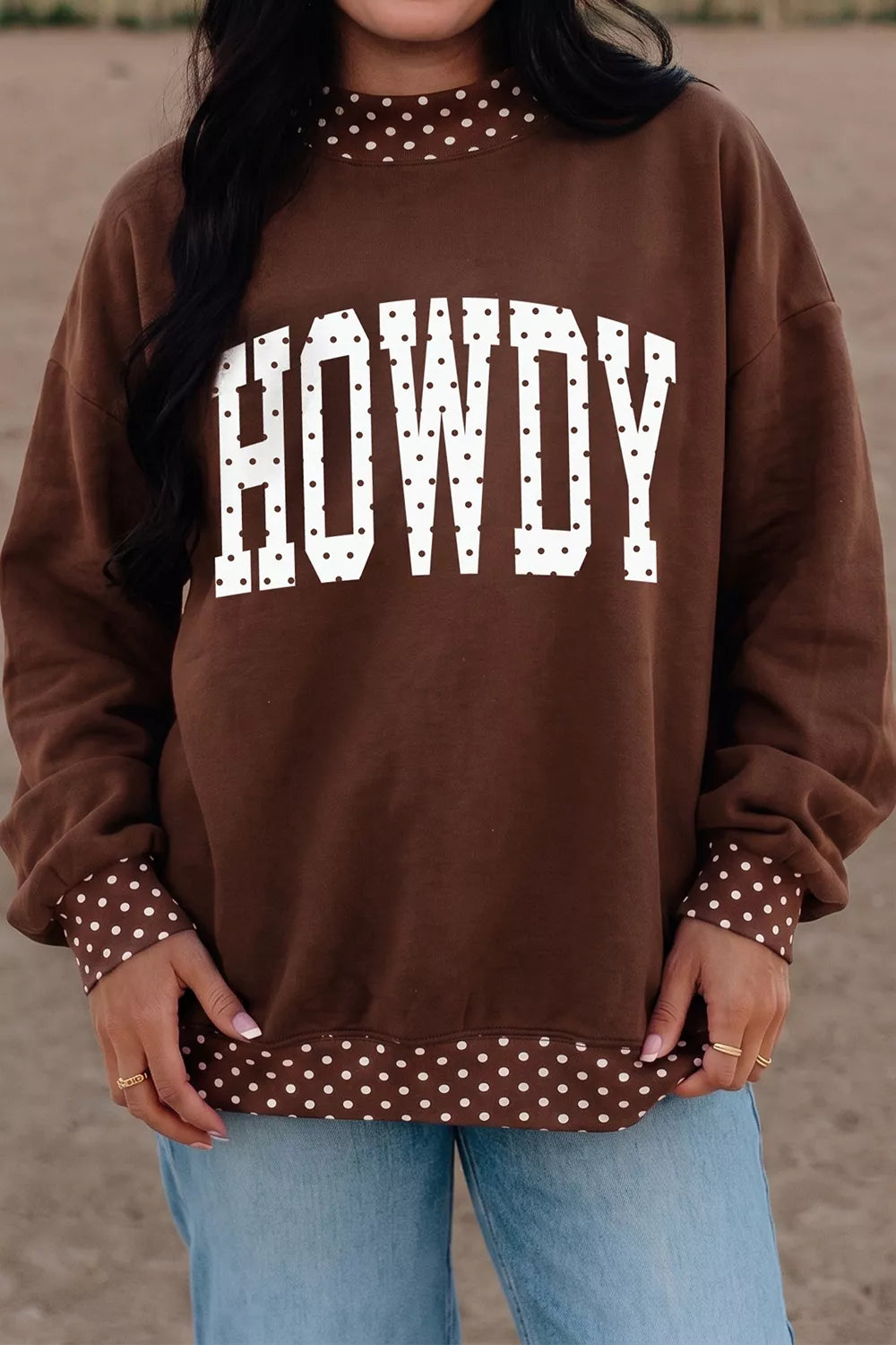 Outdoor front view of brown sweatshirt with white polka dot HOWDY lettering and trim