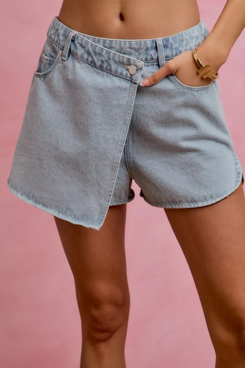 Women's washed denim skort with a wrap design and pockets.