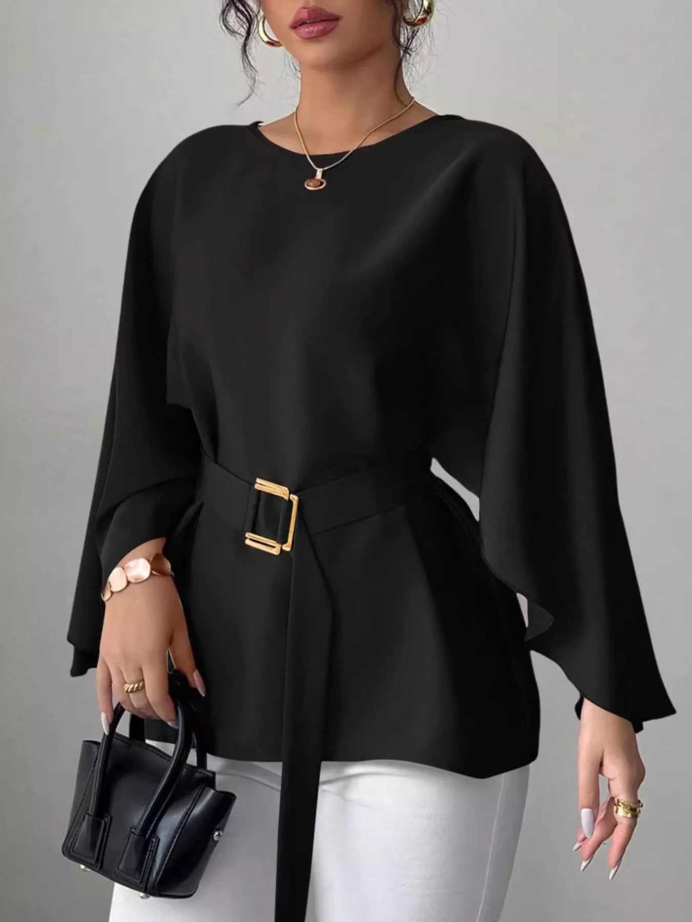Black round neck blouse front view holding black handbag with gold buckle belt