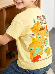 Back view of a pale yellow children's tee with a large dinosaur valley map graphic, worn on a model