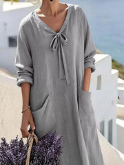 Cropped front view of grey long sleeve loose maxi dress, showing tie neck and large pockets