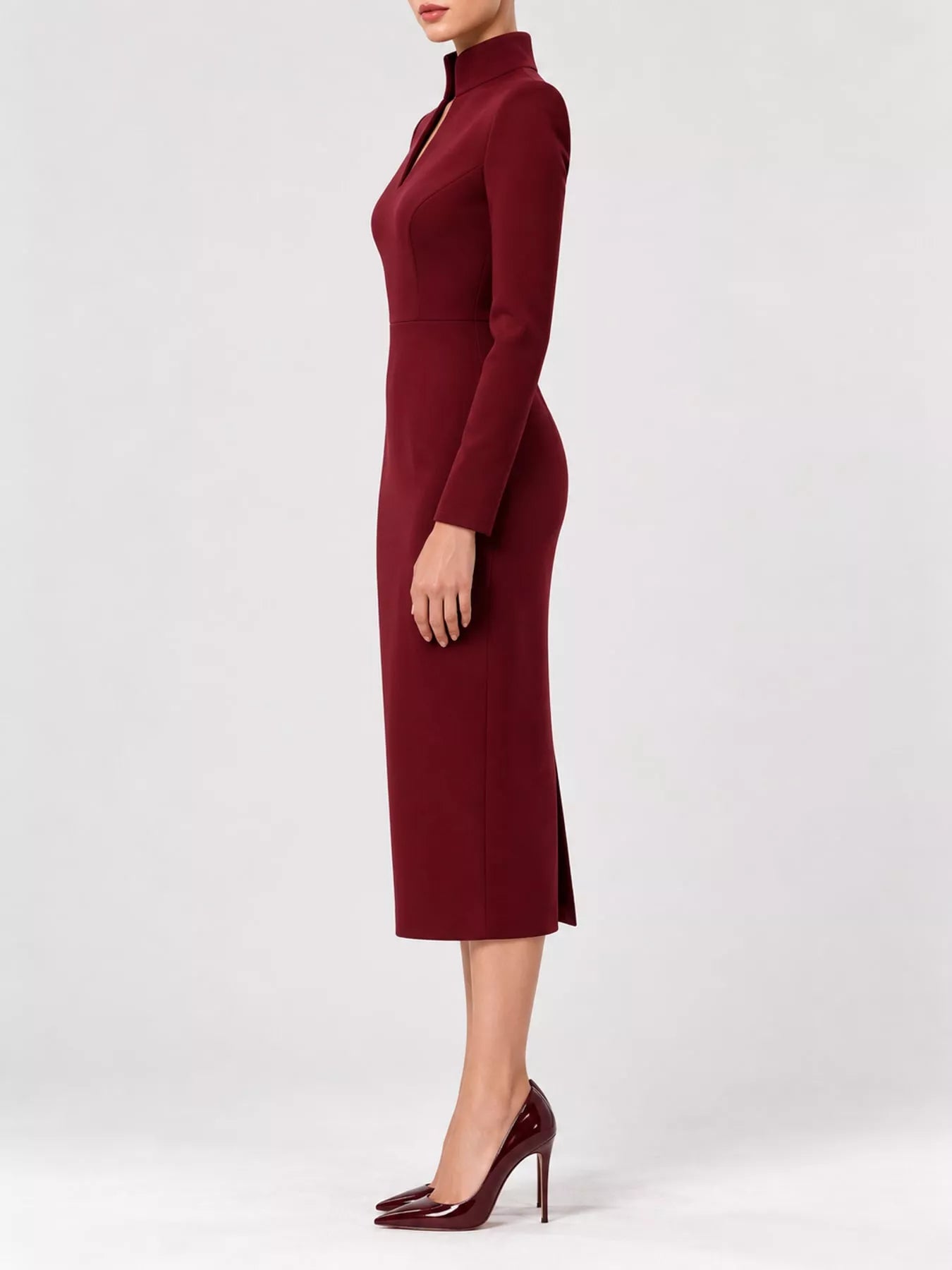 Burgundy stand collar long sleeve midi dress in side profile showing hem slit and heels