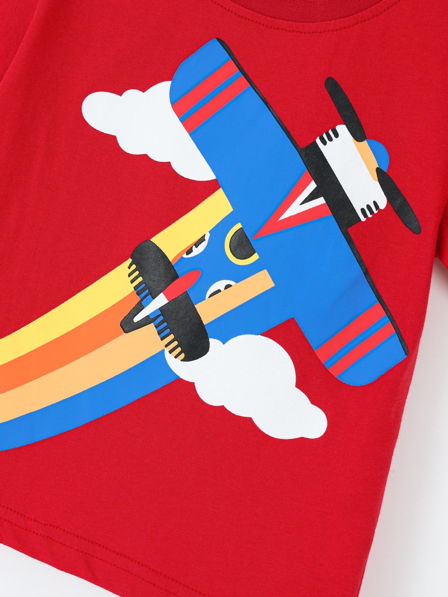 Angled close-up of blue airplane and rainbow trail graphic on red children's short sleeve t-shirt