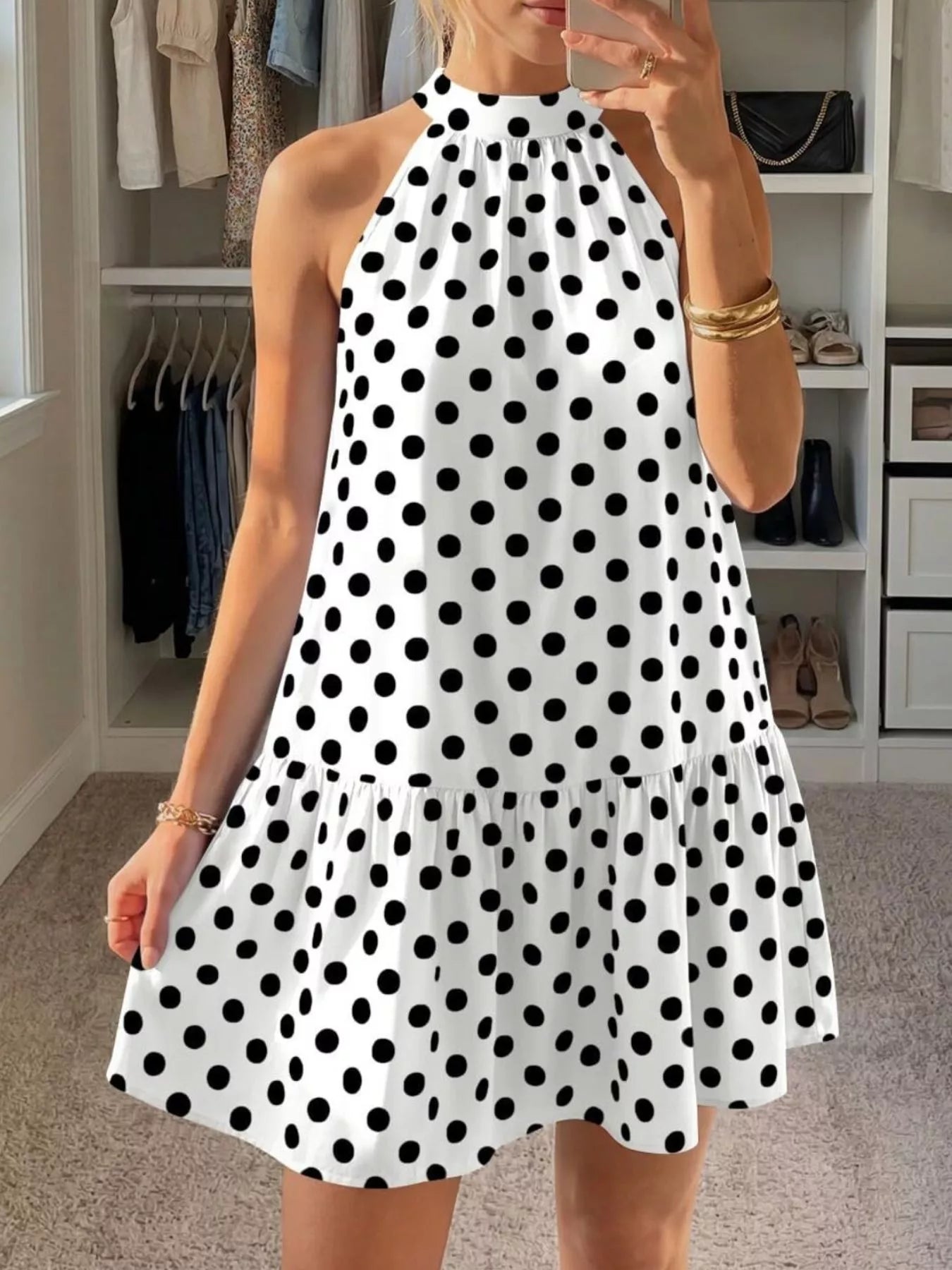 White polka dot halter neck mini dress shown front in a mirror selfie indoors