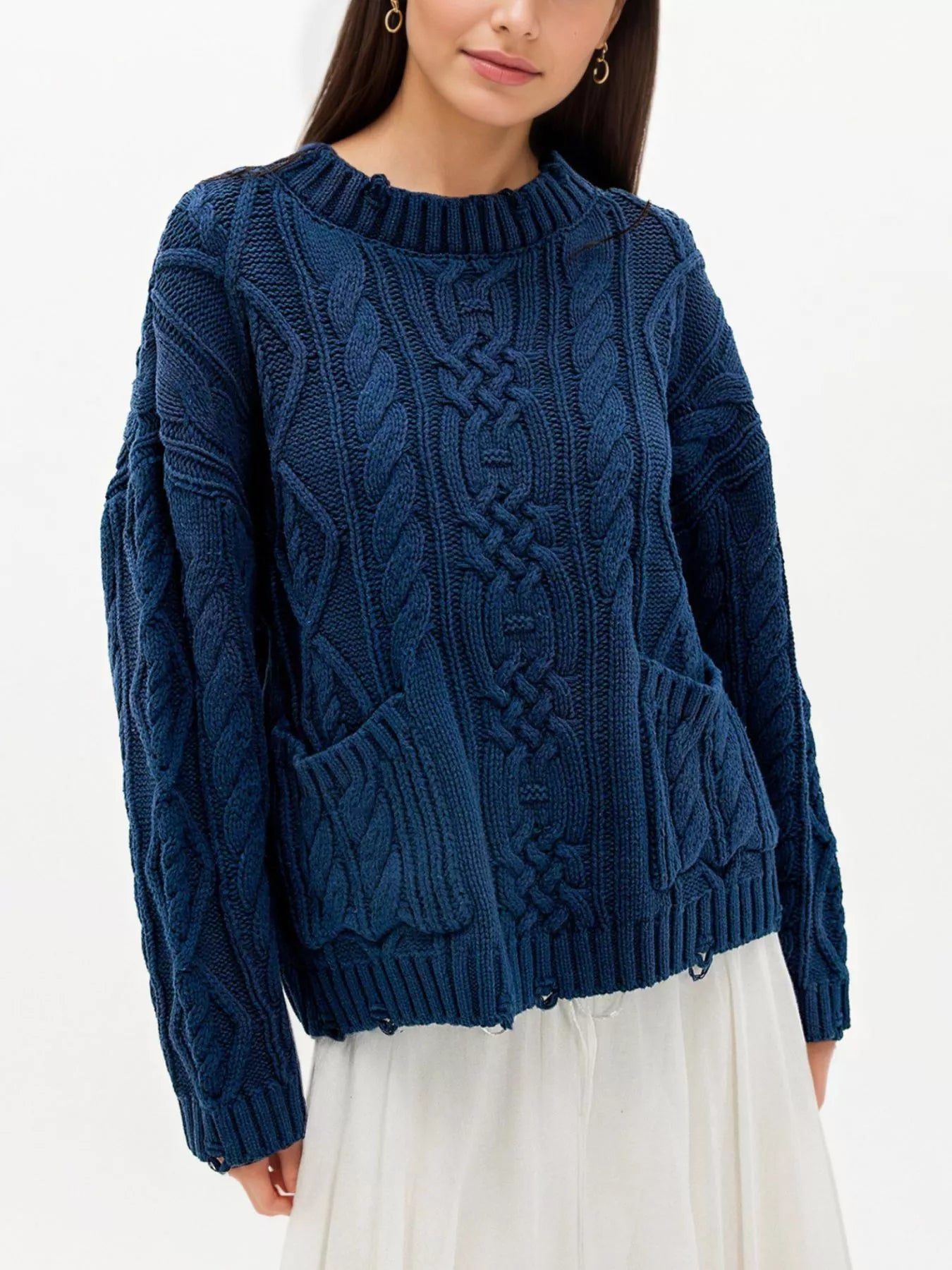 Front view of blue cable knit sweater with front pockets and white skirt