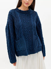 Front view of blue cable knit sweater with front pockets and white skirt
