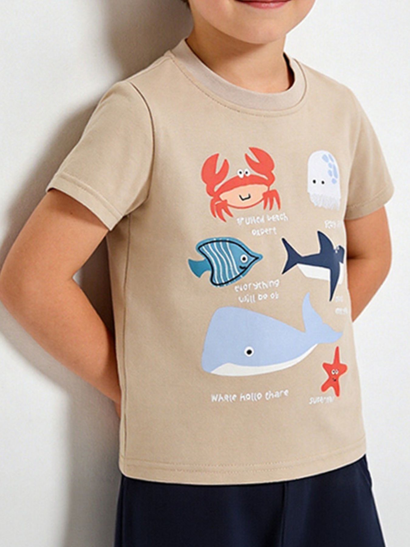 Children's tan short sleeve tee with crab, whale, shark and fish ocean graphics, shown worn in front view