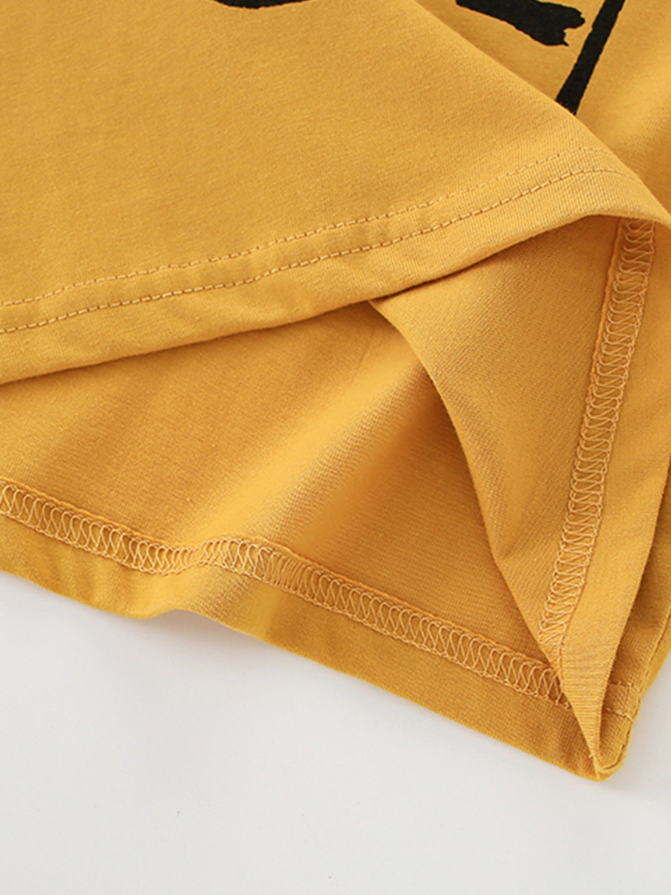 Close-up of the hem stitching and soft cotton fabric on the children's mustard t-shirt