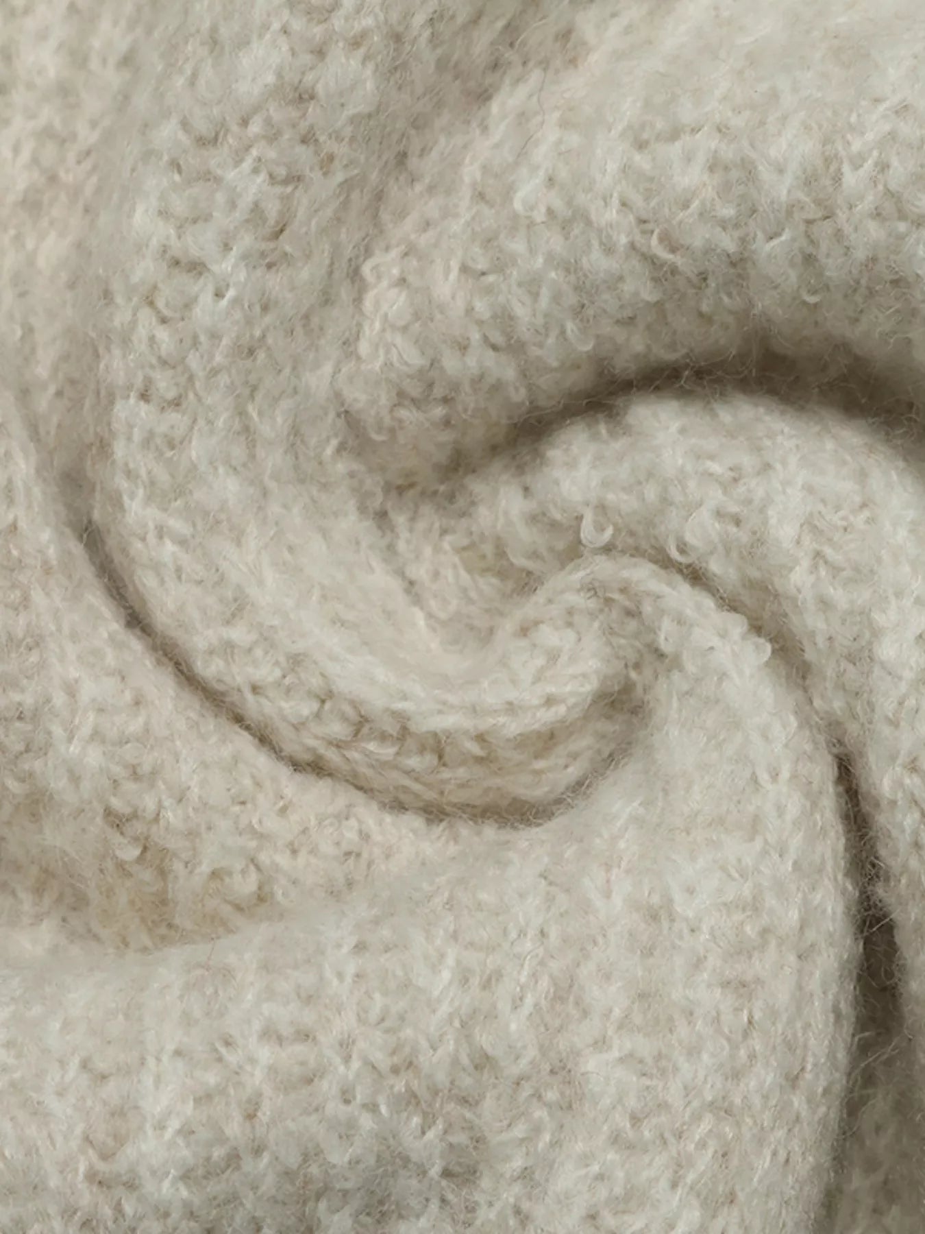 Close up of soft cream fuzzy knit fabric in a swirled fold