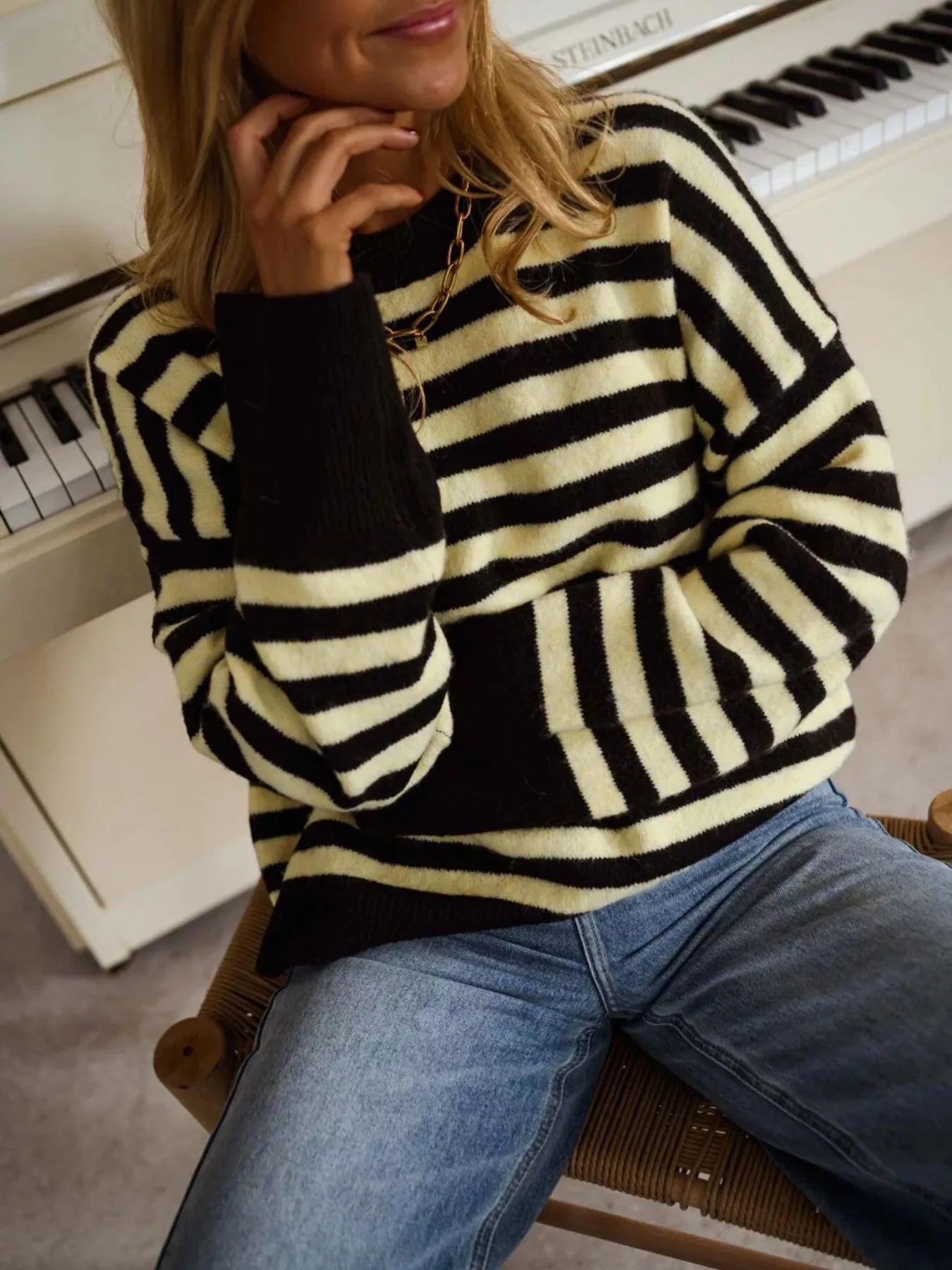Close seated on-model view of a black and yellow striped crew neck sweater