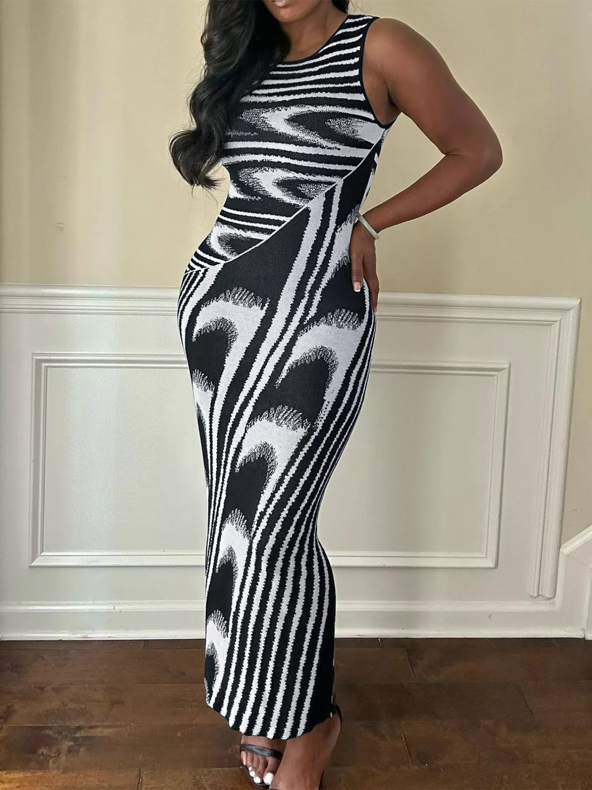Front view of a plus size black and white sleeveless bodycon maxi dress with an abstract print indoors