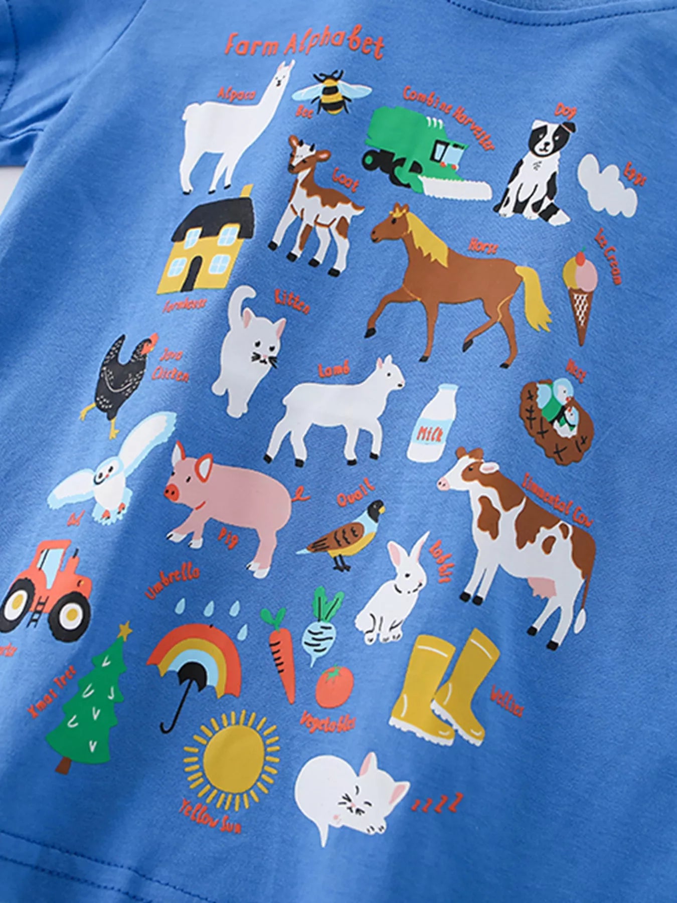 Close-up of farm alphabet print with labeled animals vehicles and farmhouse on blue fabric