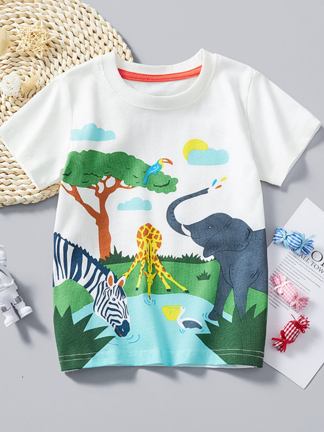 White children's round neck t-shirt laid flat with elephant zebra and giraffe safari print