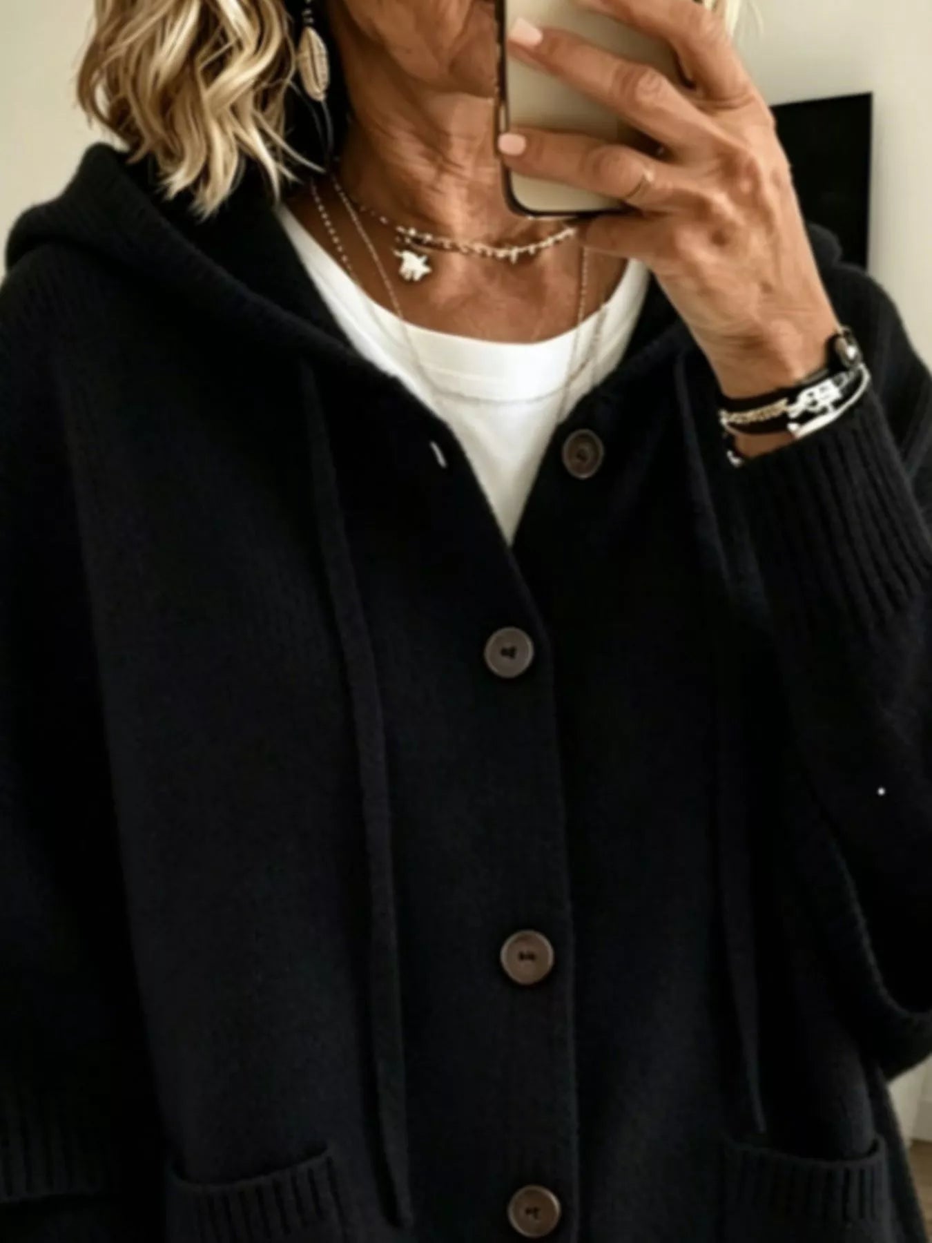 Close view of the black hooded cardigan showing drawstrings and button front