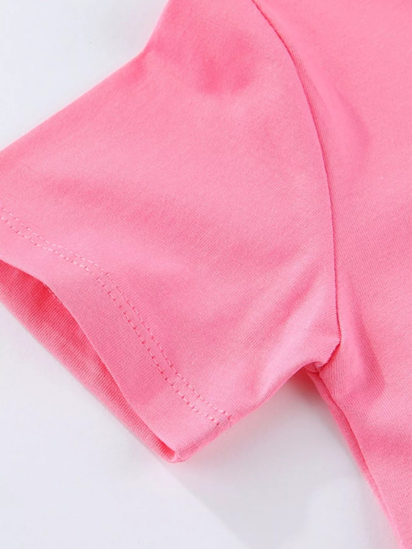 Close-up of fuchsia pink children's tee short sleeve hem stitching and smooth fabric