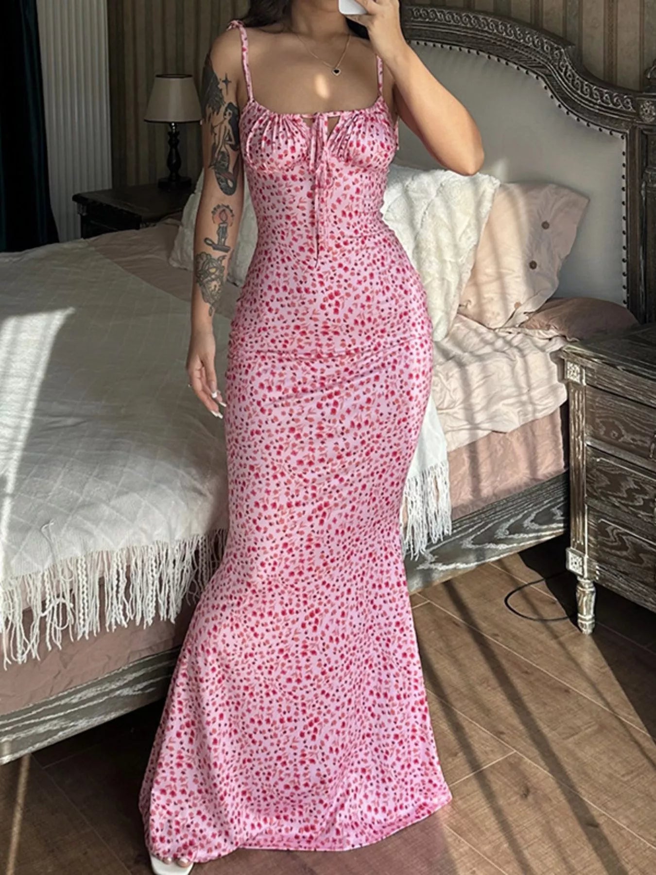 Model taking mirror selfie in pink floral print bodycon maxi dress with tie straps and flared hem