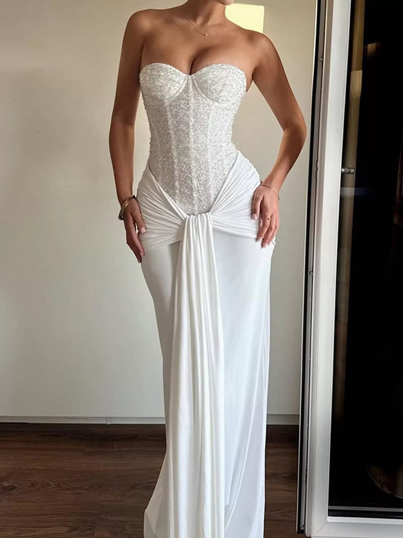 White strapless sequin corset maxi dress with draped waist on model, front view indoors