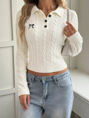 White cable knit polo sweater with black buttons and bow embroidery, model carrying shoulder bag