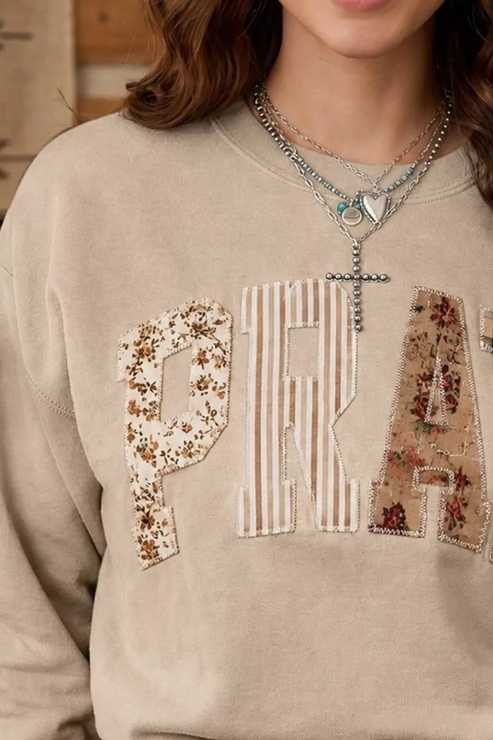 Chest close view of khaki western sweatshirt showing floral and striped patch letters