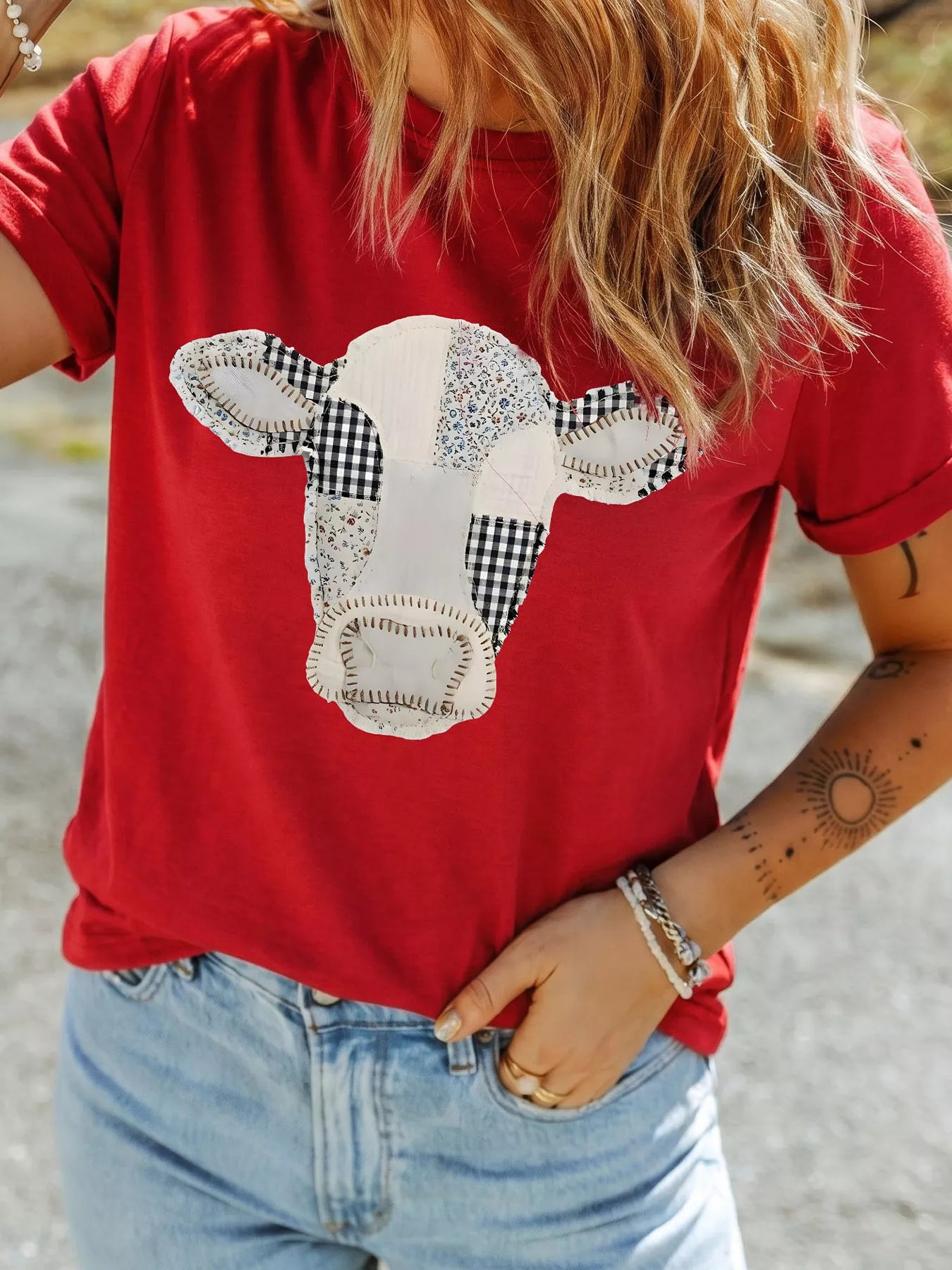 Close front view of deep red round neck casual top with patchwork cow print outdoors