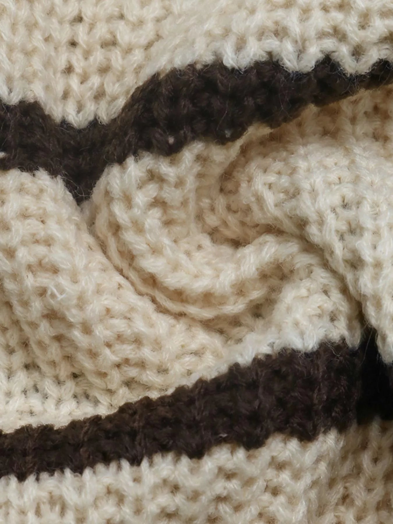 Close up showing the soft cream and brown striped knit texture of the sweater.