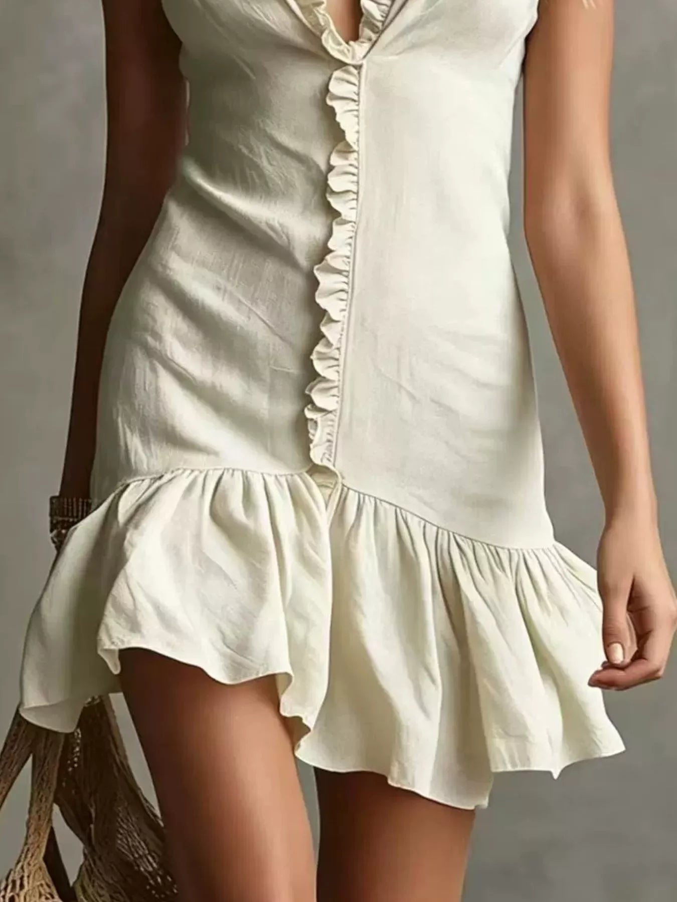 Detail view of pale apricot ruffled V neck sleeveless mini dress showing ruffled front seam