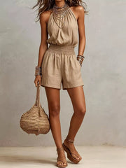 Women's khaki halter-neck romper with a smocked waist, ties, and an open back.