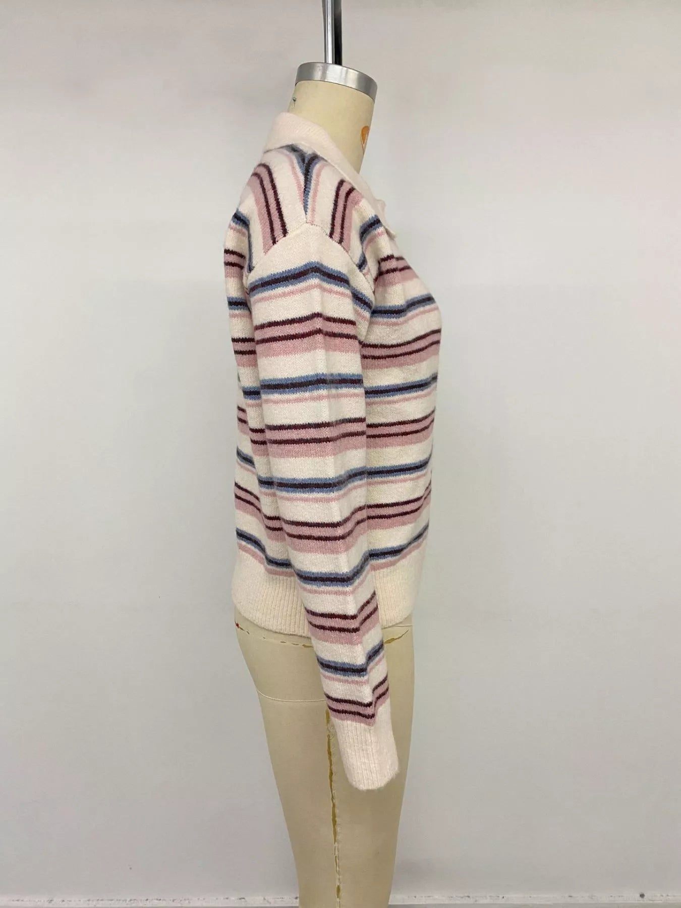 Side view of a cream striped polo sweater with long sleeves on a mannequin