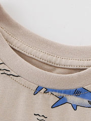 Close-up of ribbed crew neckline and shark print edge on tan children's tee