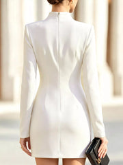 Back view of model outdoors wearing white mock neck mini dress with long sleeves and back zip