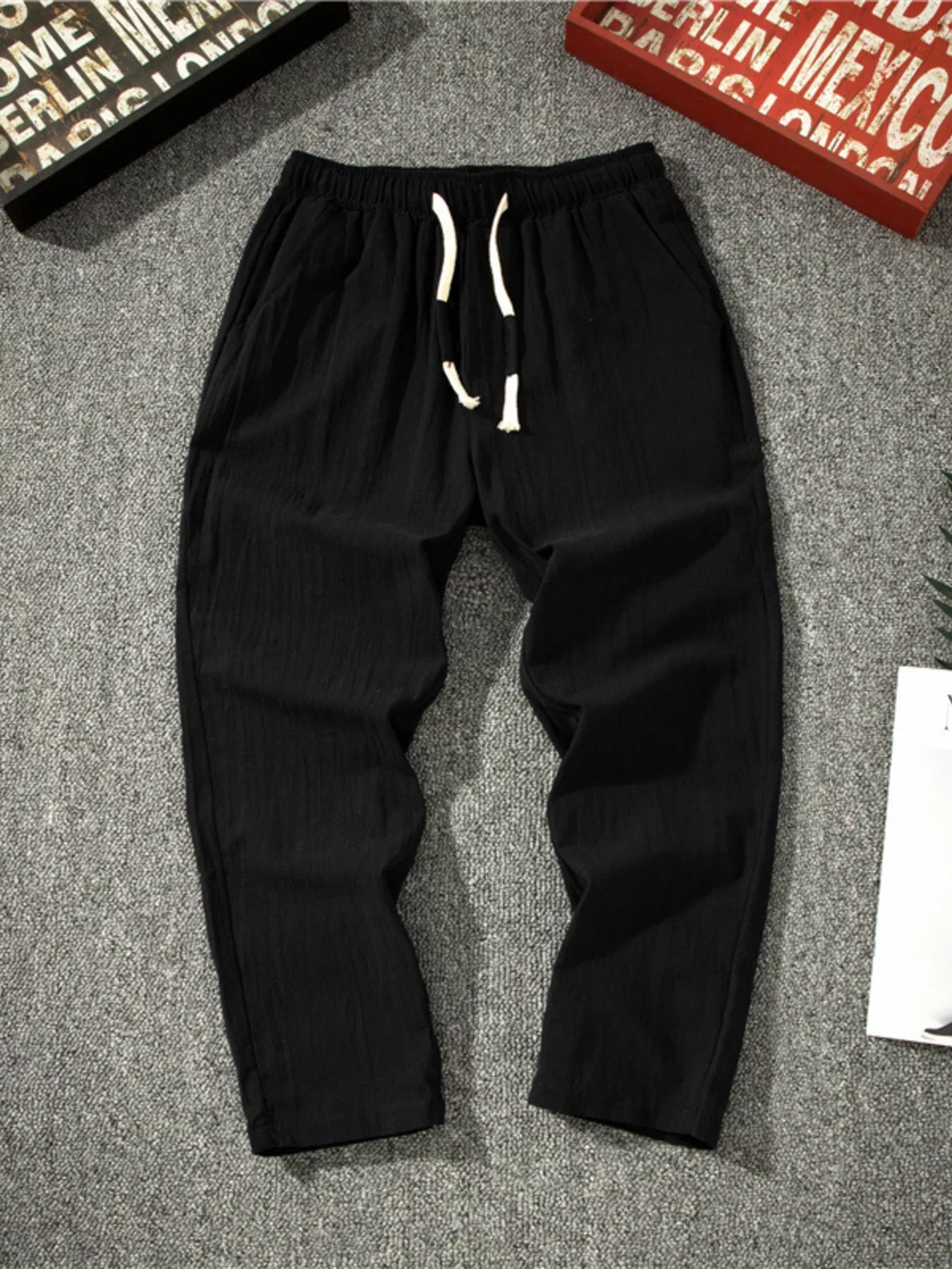 Men's black loose-fit pants with a drawstring waist and pockets.