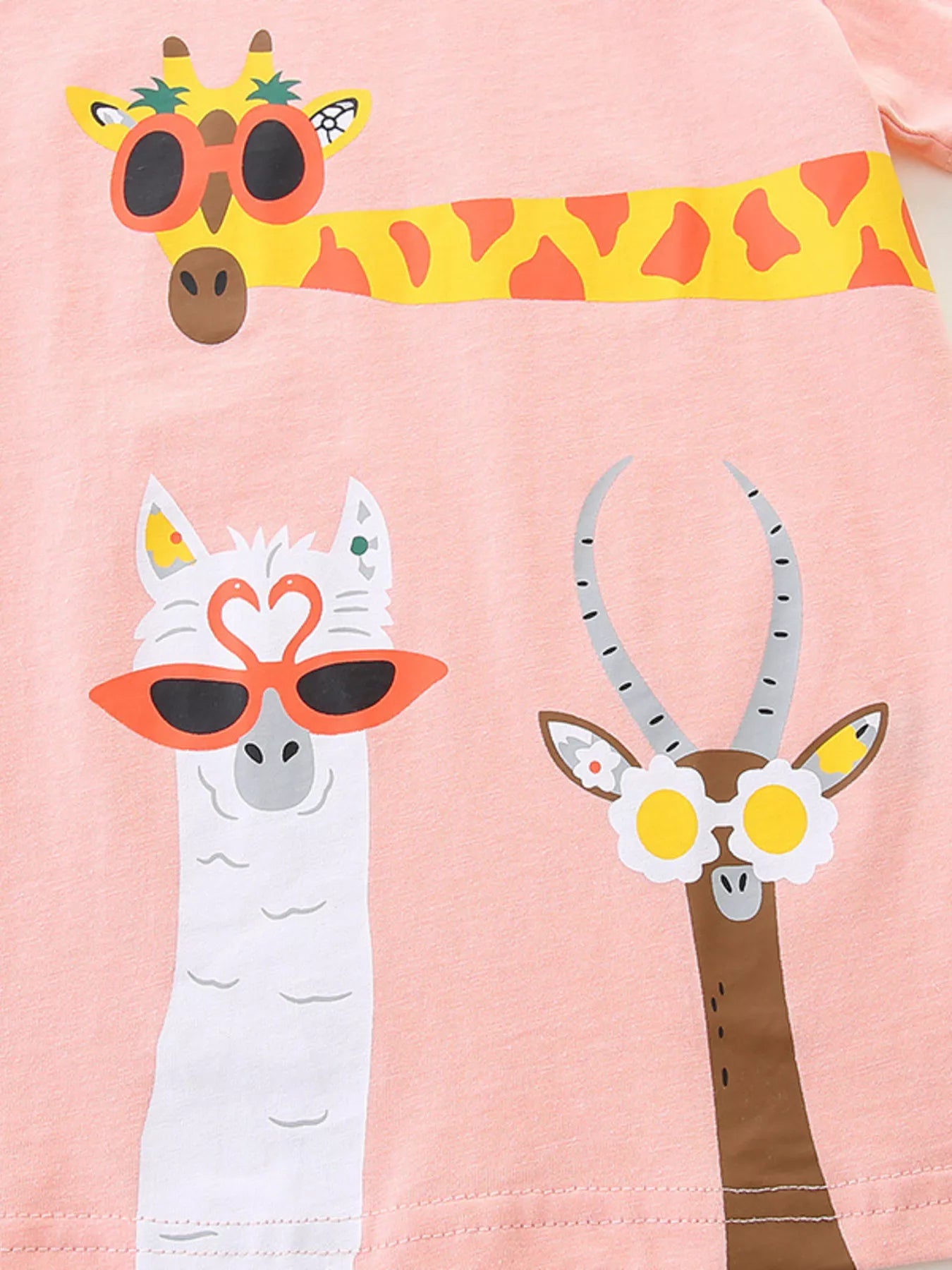 Close-up of cartoon animal prints with giraffe llama and antelope wearing novelty glasses on pink fabric
