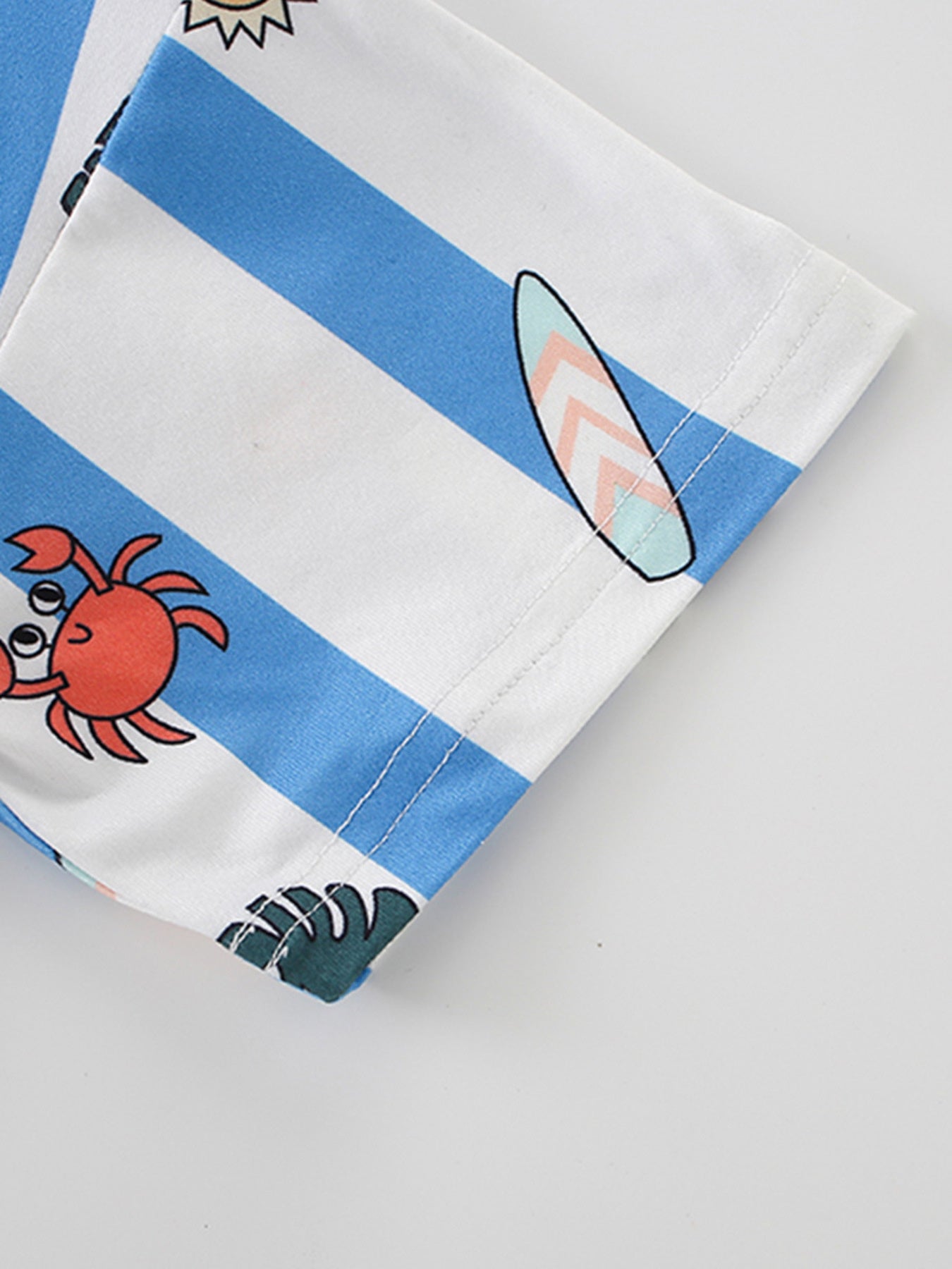 Close view of a striped sleeve with crab and surfboard prints on a children's cartoon tee