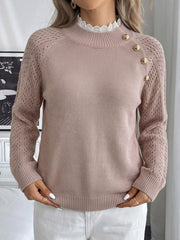 Front view of a pink mock neck sweater with openwork sleeves and gold shoulder buttons