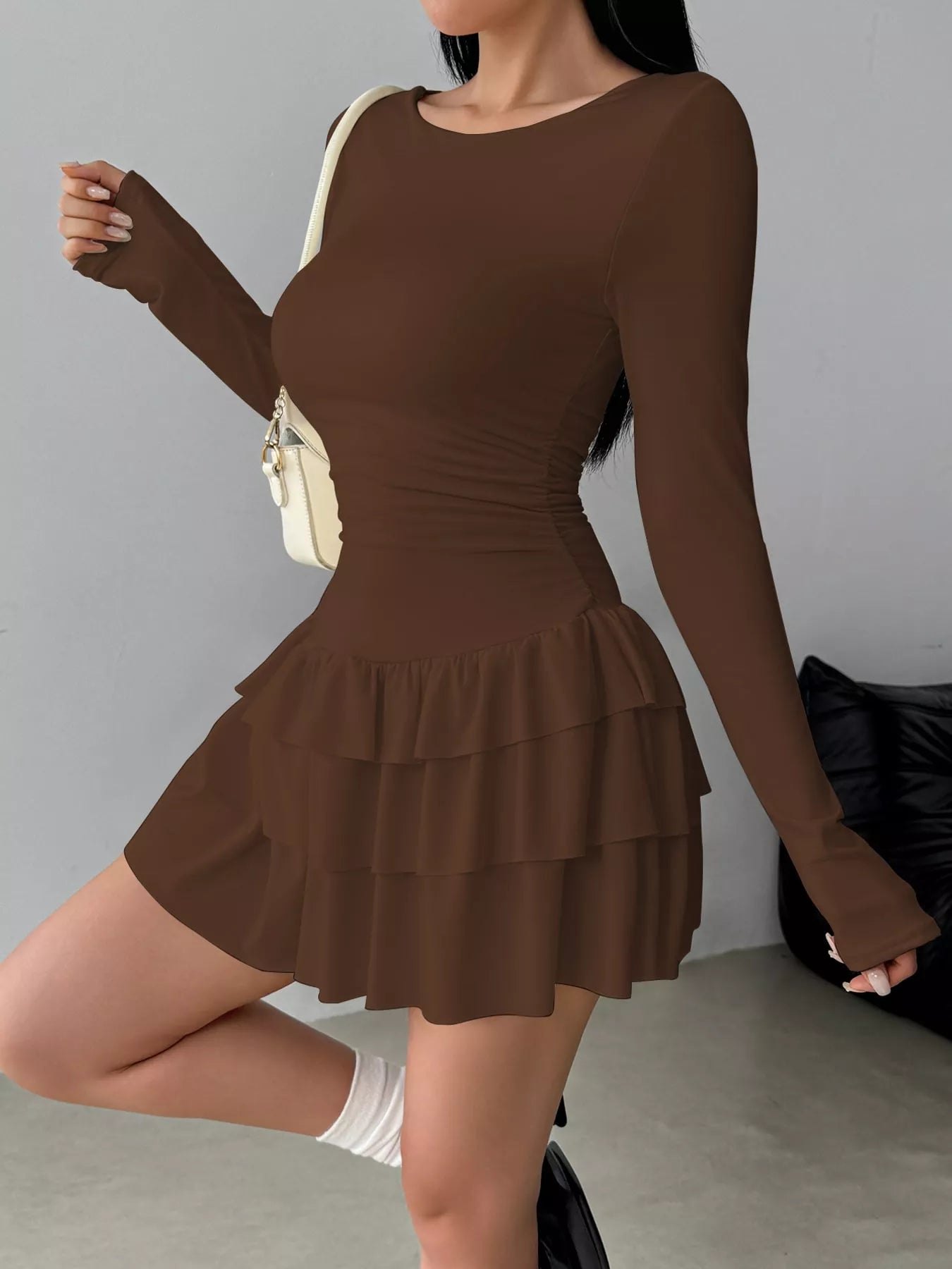 Coffee long sleeve mini dress worn in a side view showing the ruched waist and tiered ruffle skirt