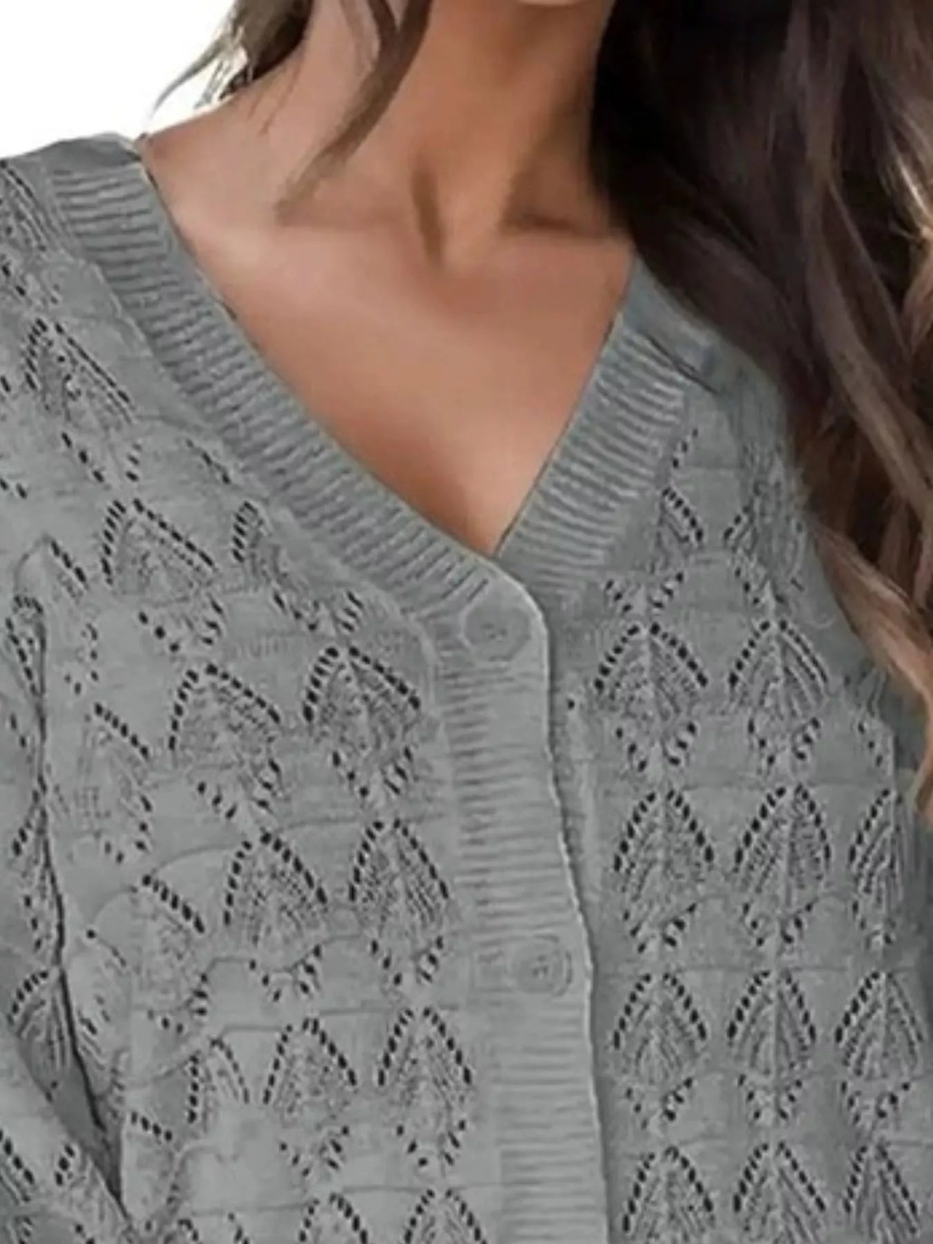 Close view of gray openwork knit cardigan showing V neckline and button front.