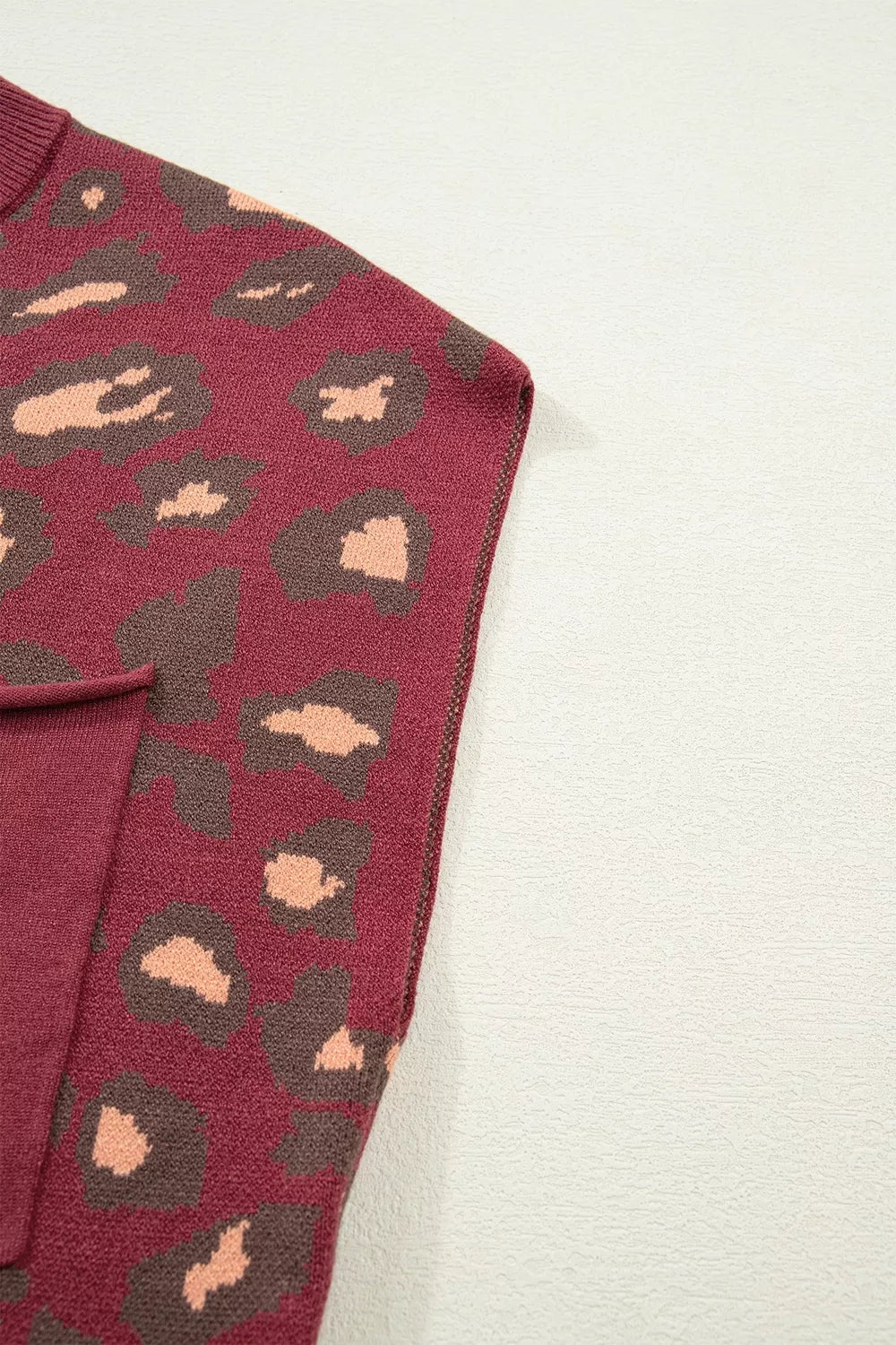 Close-up of the deep red leopard print knit top side seam and pocket