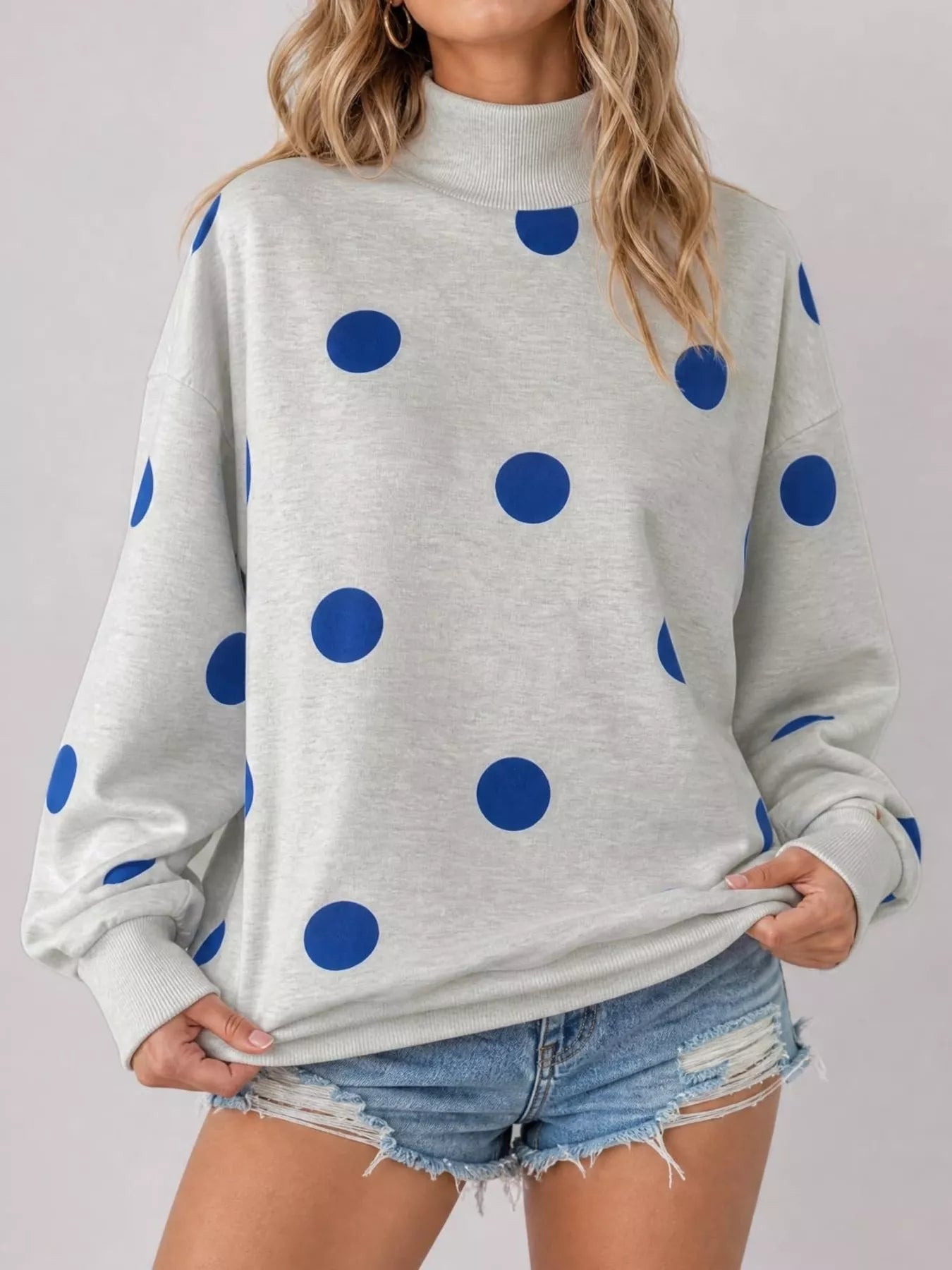 Front studio view of light gray mock neck oversized sweatshirt with large blue polka dots