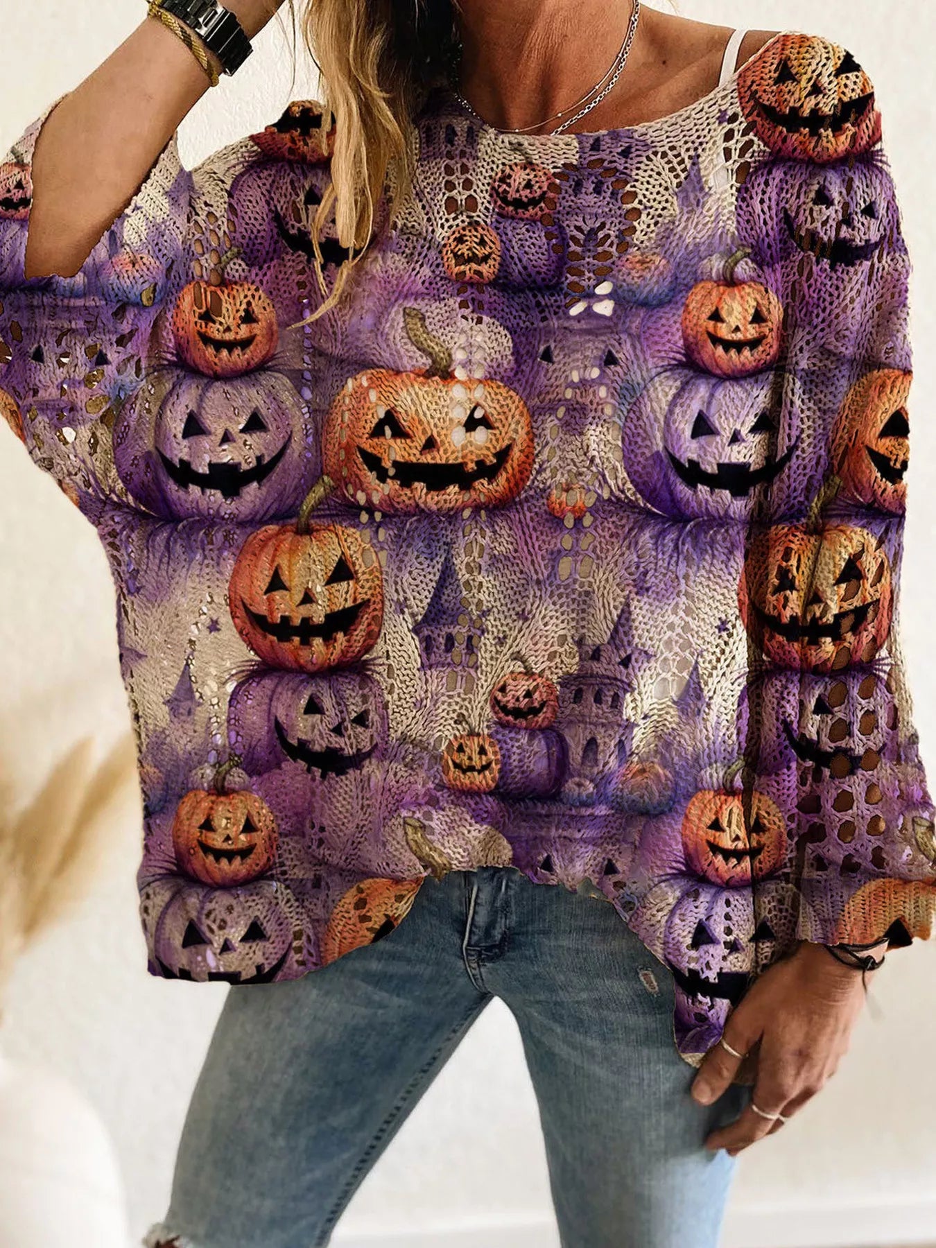 Front view of a purple openwork knit cover up with orange and purple jack o lanterns.