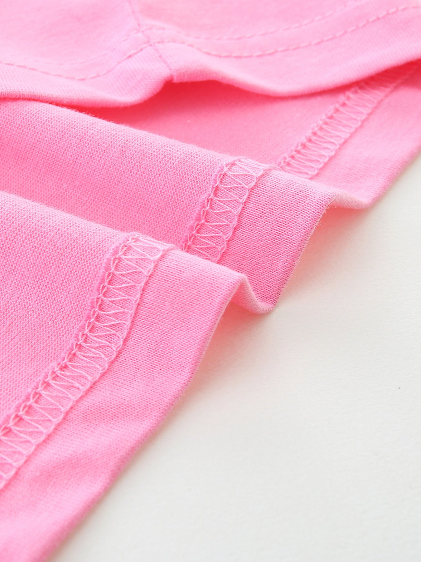 Close up of pink children's t-shirt hem stitching and smooth cotton fabric texture