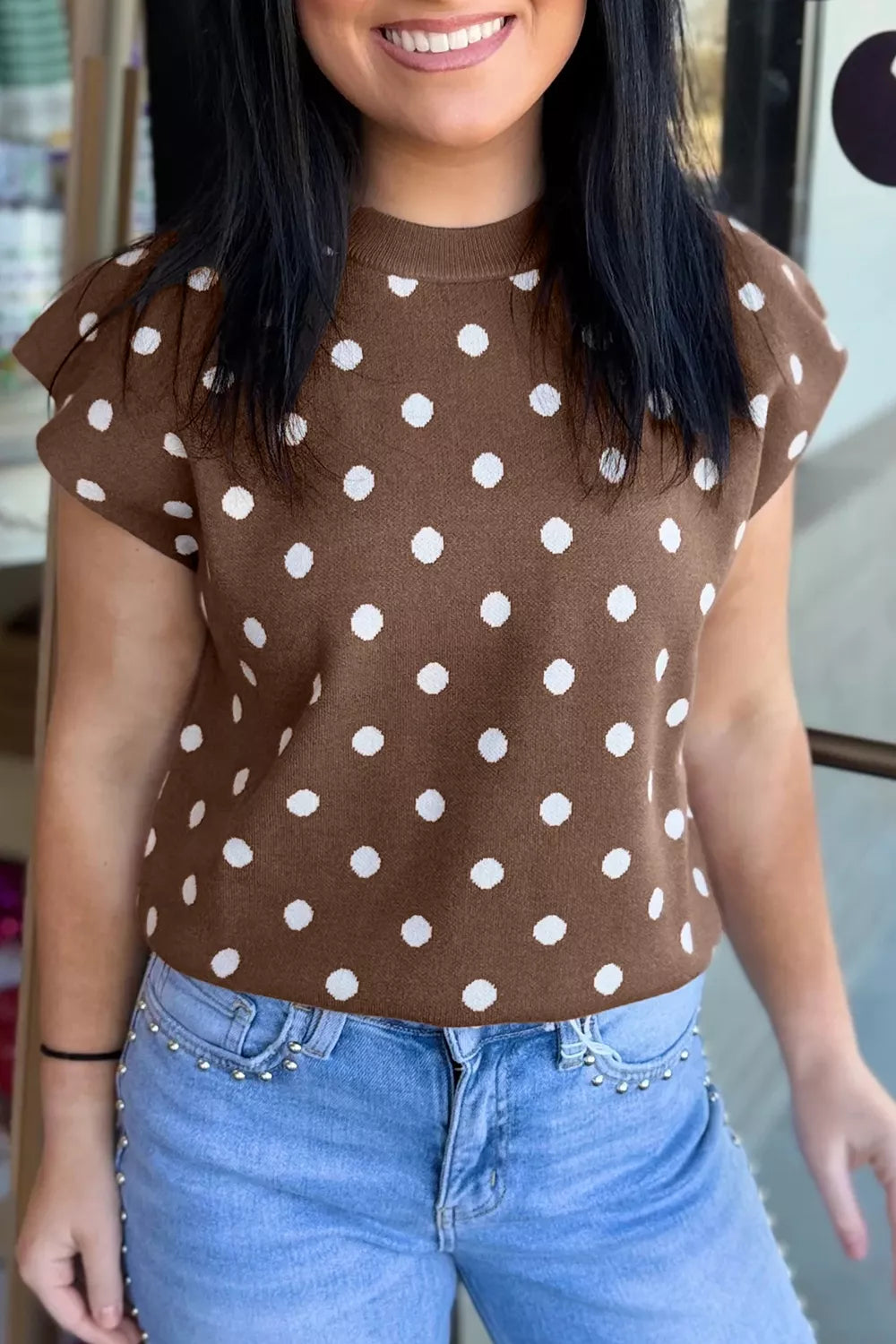 Front view of a dark brown knit sweater with white polka dots and short dolman sleeves